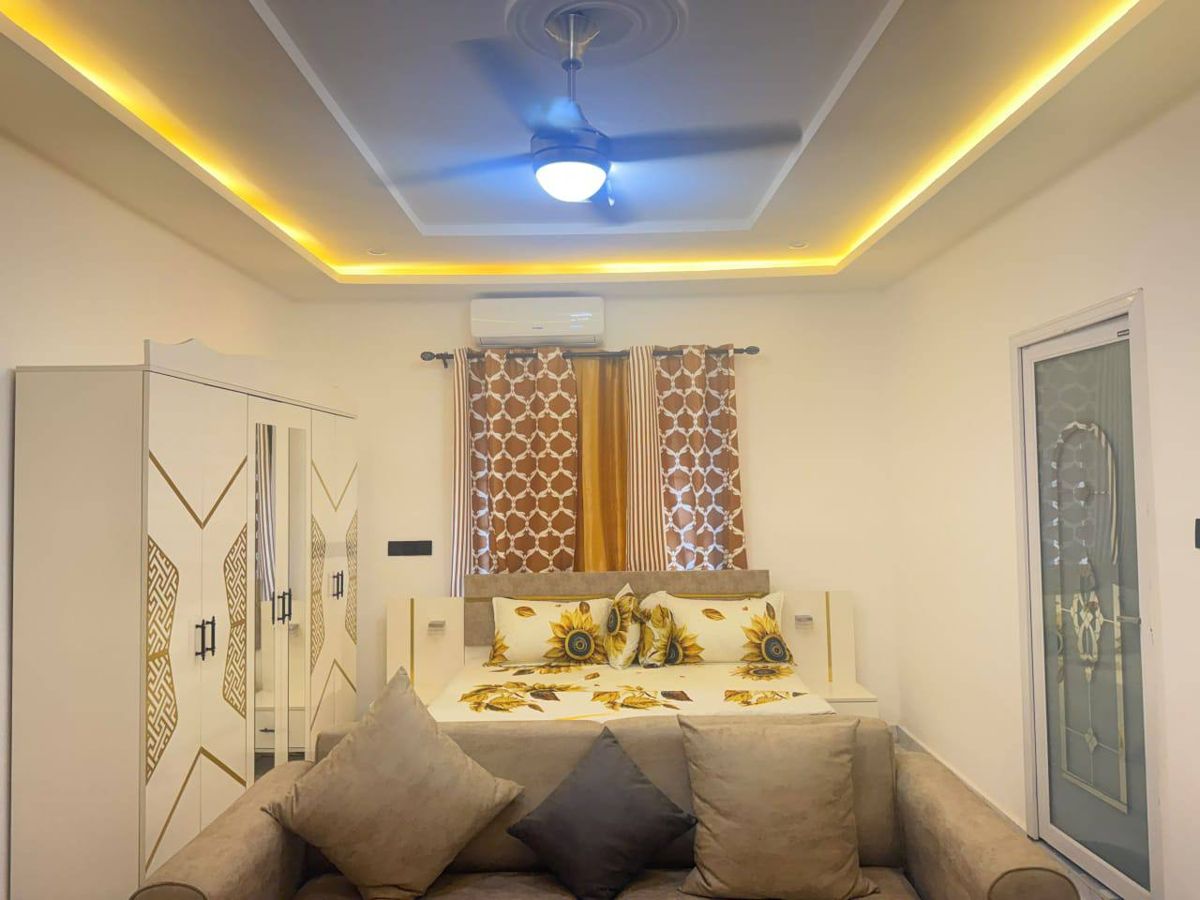 Studio apartment with gold cove lighting, ceiling fan and sunflower bedding